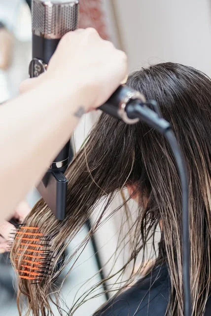 Stylist blow drying woman's wet hair with round brush, salon haircare at Yellow B