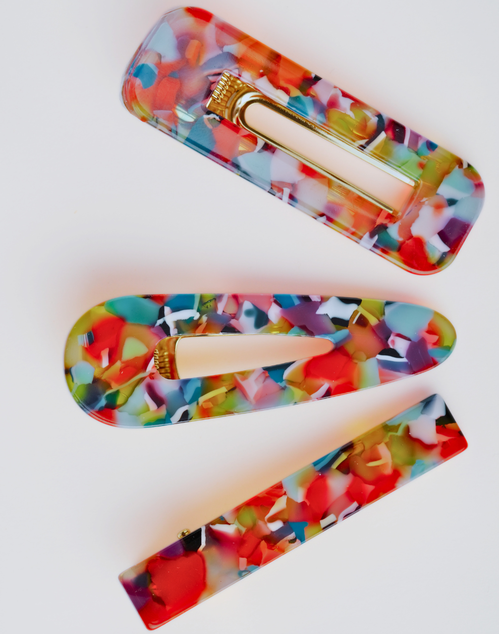 Set of three multicolour hairclips with gold hardware on a white background.