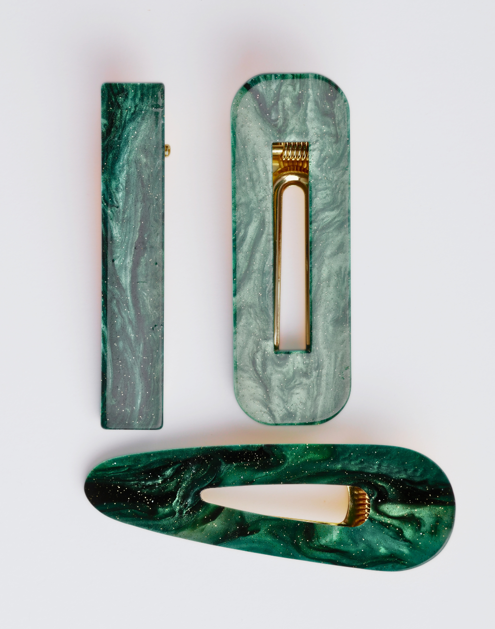 Three green marbled hairclips on a white background