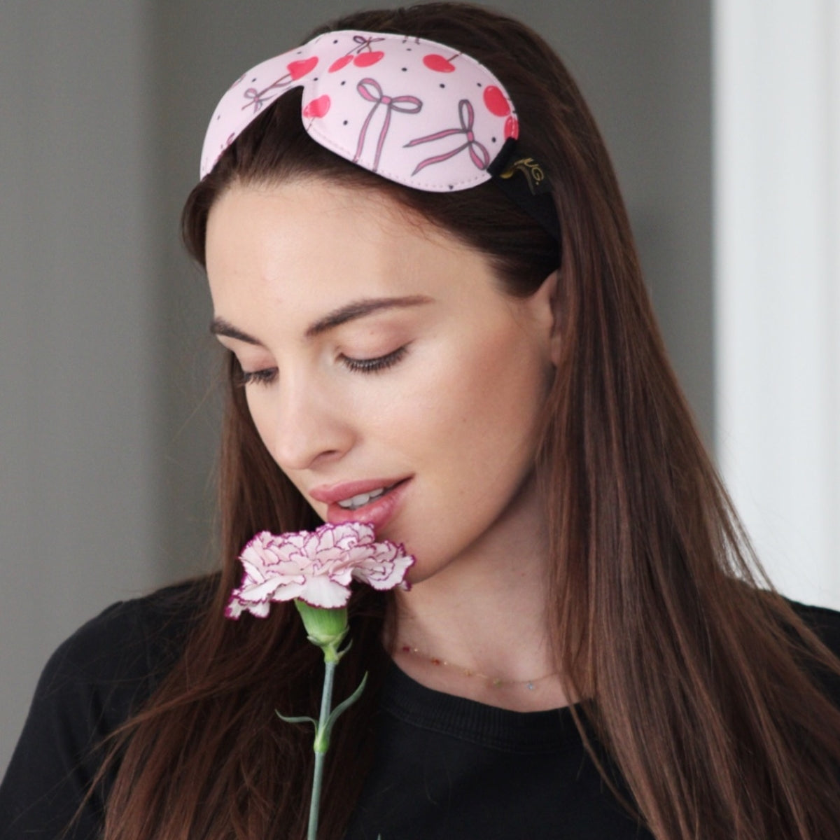 Model with a SMUG Pink Cherries contoured sleep mask resting on her head.