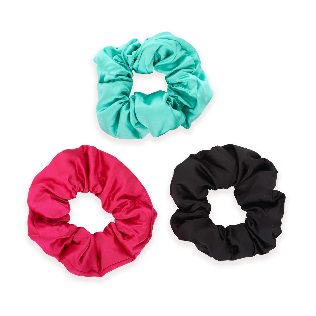 Three SMUG satin scrunchies in aqua, pink, and black on a white background