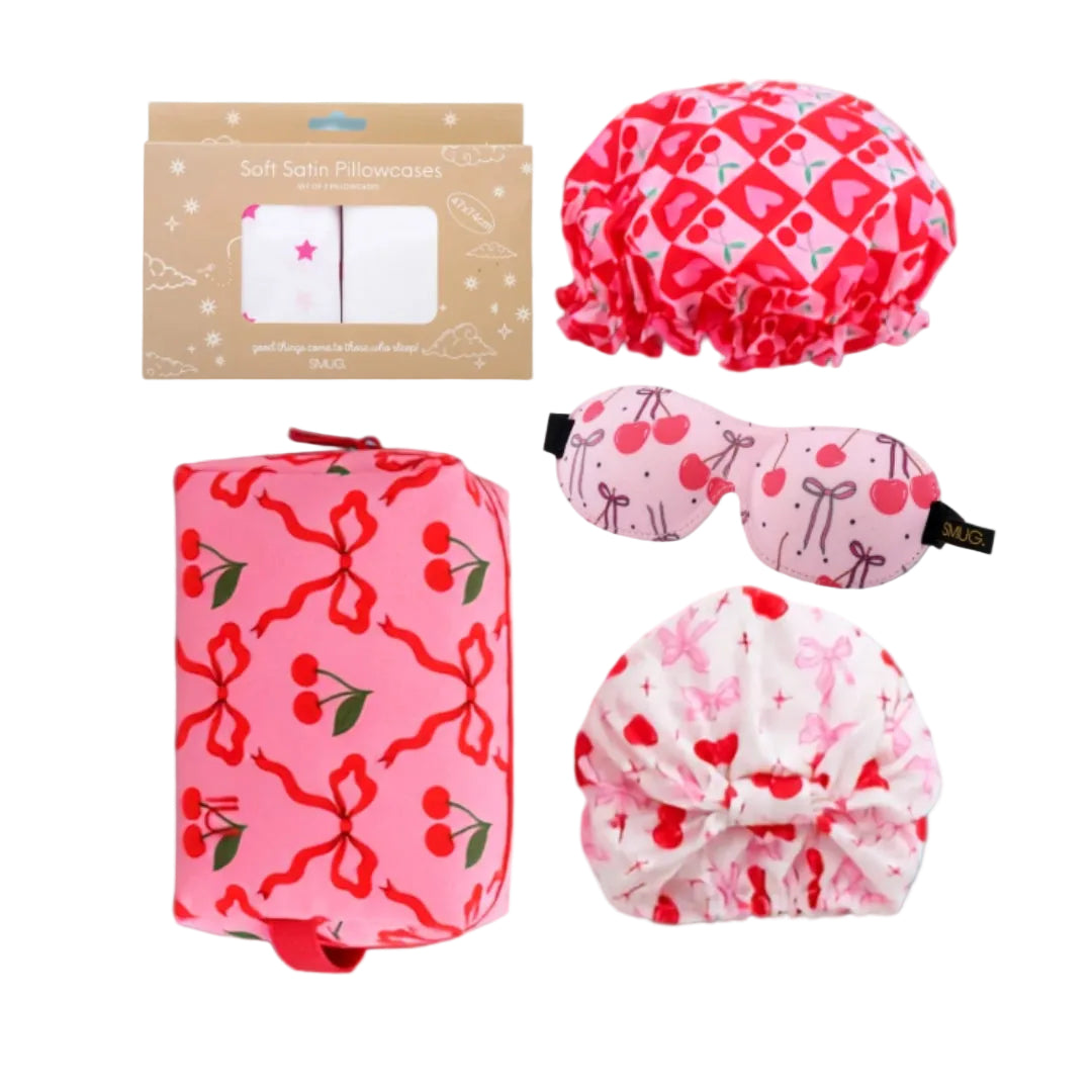 SMUG The Cherry Dream Gift Set laid flat with packaged pillowcases, shower cap, sleep mask, sleep turban and wash bag.